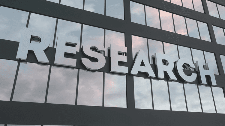 Building facade with large reflective letters spelling "RESEARCH" against a cloudy sky.